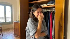 Donna sorridente davanti a un armadio aperto in una camera luminosa.