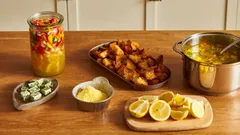 Ingredienti e contorni per zuppa indiana: pane, limoni, spezie, sottaceti su tavolo di legno.